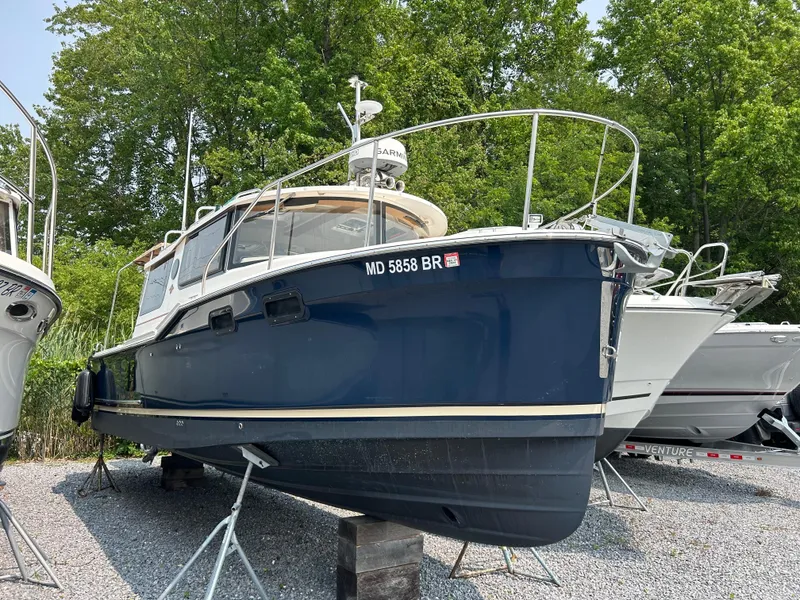 The Image of 2021 Ranger Tugs R-27 boat on stands, blue hull, parked outdoors. - 1