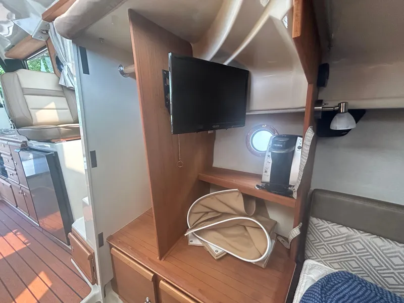 Slide: The Image of 2021 Ranger Tugs R-27 interior with TV, porthole, and wooden cabinetry. - 10