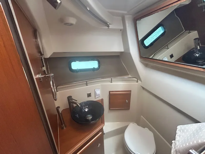 Slide: The Image of 2021 Ranger Tugs R-27 boat bathroom with sink, mirror, and window. - 11
