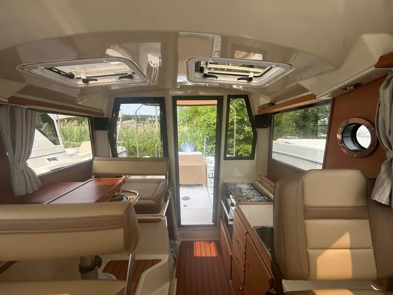 Slide: The Image of Interior of 2021 Ranger Tugs R-27 boat, featuring seating and kitchen area. - 14