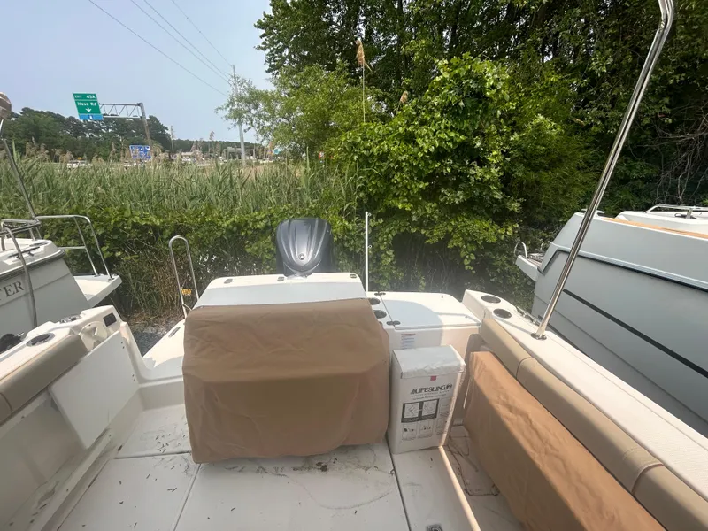 Slide: The Image of 2021 Ranger Tugs R-27 boat interior with covered seating and lush greenery background. - 15