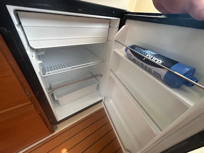 Slide: The Image of Open refrigerator inside 2021 Ranger Tugs R-27 boat, showing shelves and a water filter. - 8