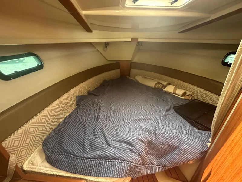 Slide: The Image of 2021 Ranger Tugs R-27 cabin interior with cozy bed and porthole windows. - 9