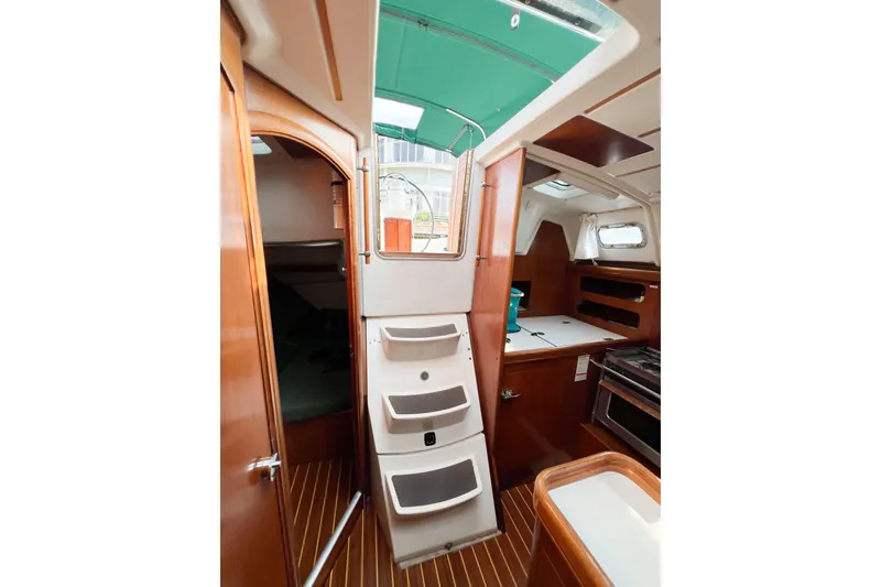 Slide: The Image of Interior of 2002 Beneteau 361 sailboat with wooden cabinetry and compact kitchen area. - 12