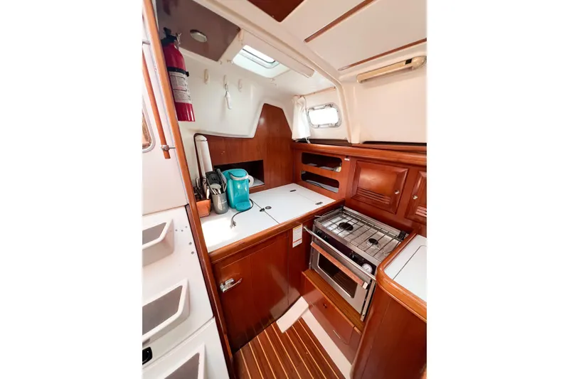 Slide: The Image of 2002 Beneteau 361 yacht kitchen with wood cabinetry, stove, and compact design. - 13
