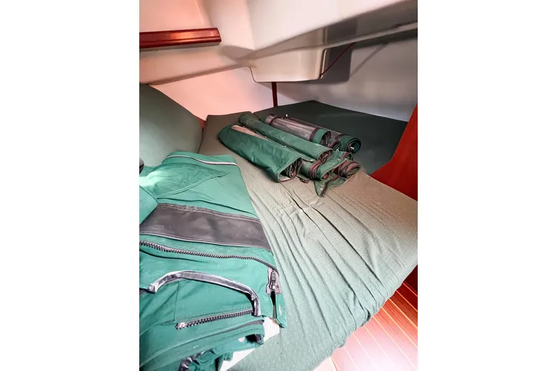 Slide: The Image of Interior of 2002 Beneteau 361 sailboat with green fabric and rolled-up covers. - 6