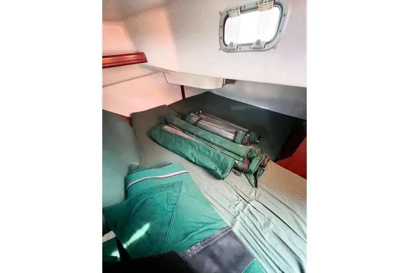 Slide: The Image of Interior cabin of 2002 Beneteau 361 sailboat with green cushions and rolled-up sails. - 7