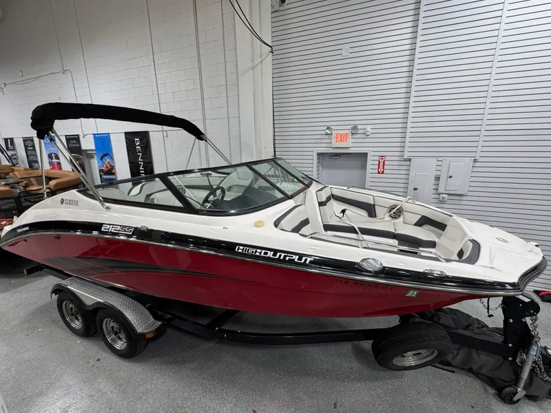 The Image of 2014 Yamaha Boats 212X in showroom, red and white design, on trailer. - 0