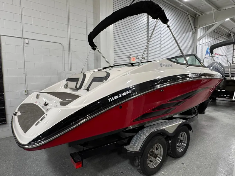 Slide: The Image of 2014 Yamaha Boats 212X, red and white, twin engine, on trailer in showroom. - 1