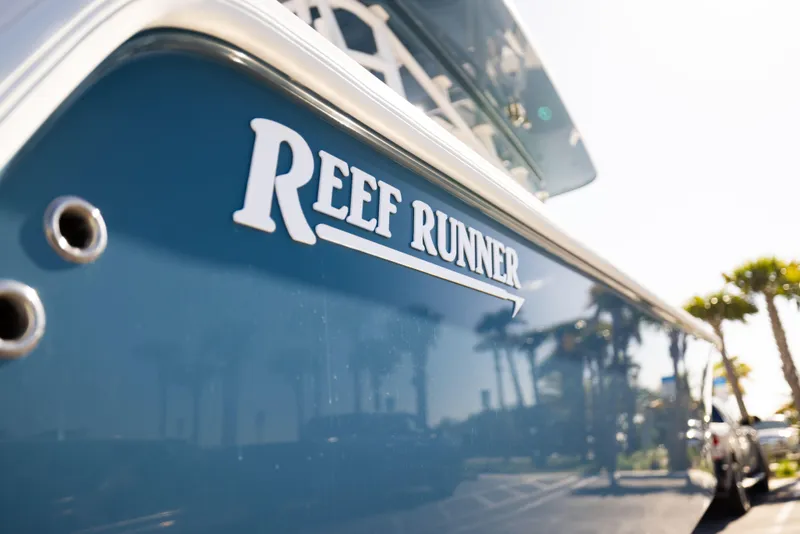 Slide: The Image of 2026 Reef Runner 340 boat with logo, sunny day reflection. - 18