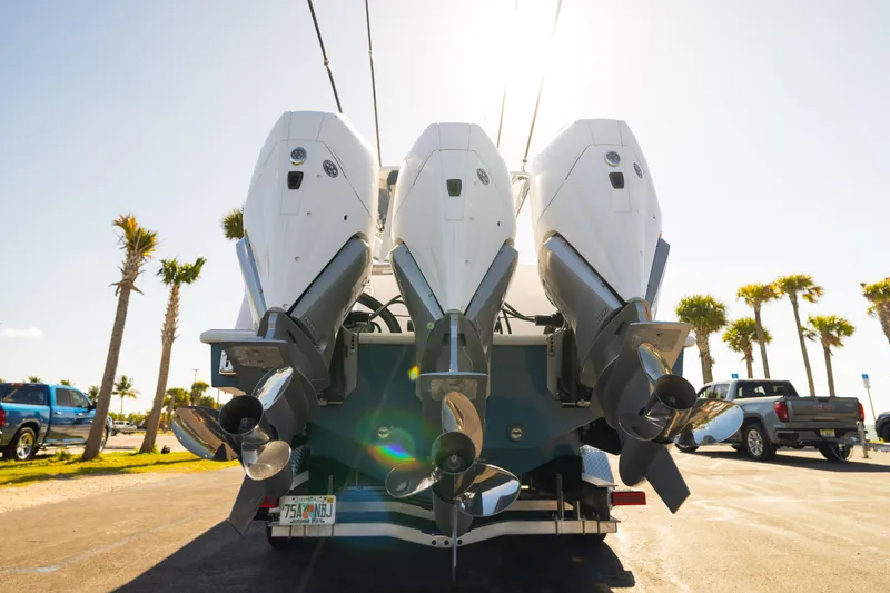 Slide: The Image of Triple outboard motors on a 2026 Reef Runner 340 boat, parked under sunny skies. - 4