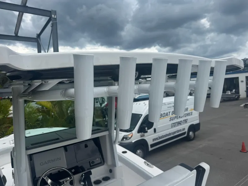 Slide: The Image of 2026 Blackfin 262 HB boat with rod holders, overcast sky, and parked van in background. - 21