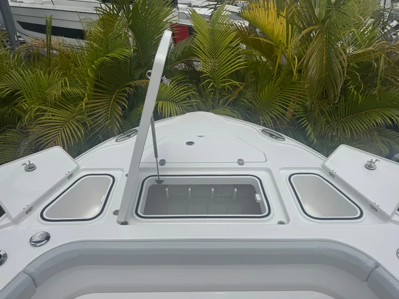 Slide: The Image of 2026 Blackfin 262 HB boat deck with open storage compartments, surrounded by lush greenery. - 31