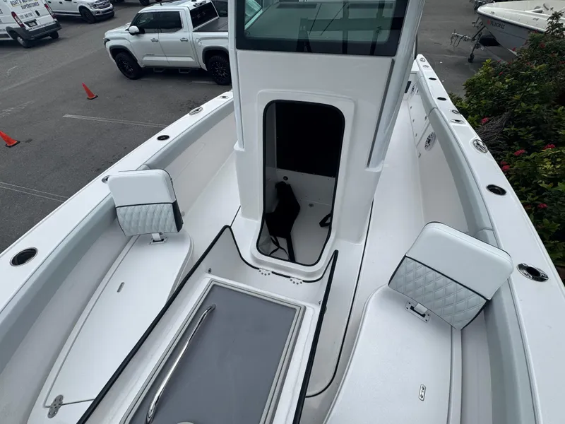 Slide: The Image of 2026 Blackfin 262 HB boat interior with seating and storage, parked near vehicles. - 37