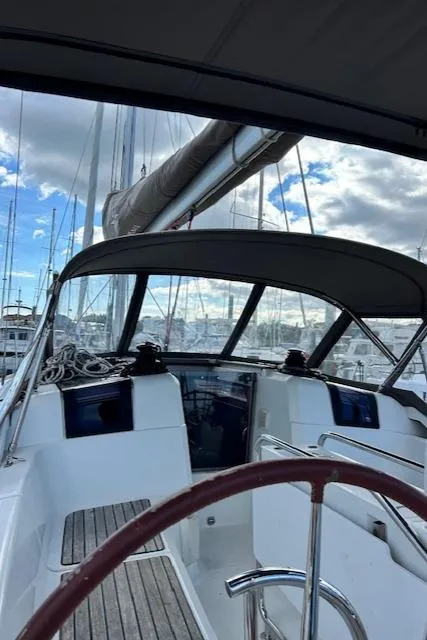 Slide: The Image of 2012 Jeanneau Sun Odyssey 379 sailboat cockpit with steering wheel and canopy, docked at marina. - 12
