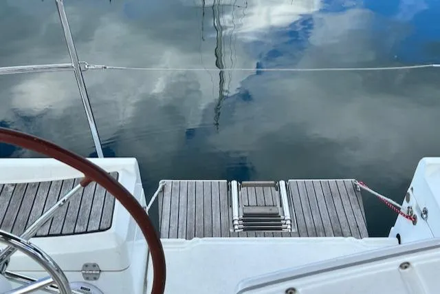 Slide: The Image of Jeanneau Sun Odyssey 379 sailboat deck with wooden steps, reflecting sky on water, 2012 model. - 17