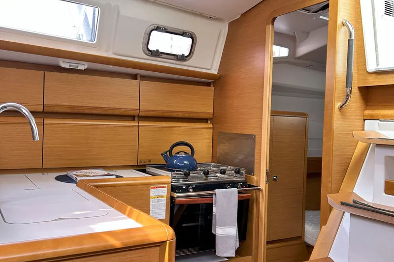 Slide: The Image of Interior of 2012 Jeanneau Sun Odyssey 379 sailboat, featuring a compact kitchen with wooden cabinetry. - 31