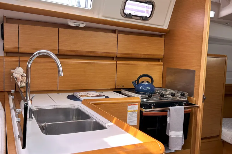 Slide: The Image of Interior of 2012 Jeanneau Sun Odyssey 379 yacht kitchen with sink, stove, and wooden cabinets. - 32