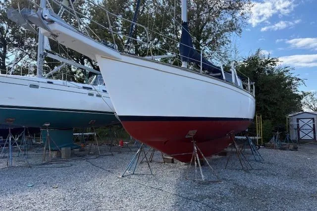 Slide: The Image of 1987 Island Packet 38 sailboat on stands, white hull, red bottom, outdoor storage. - 12