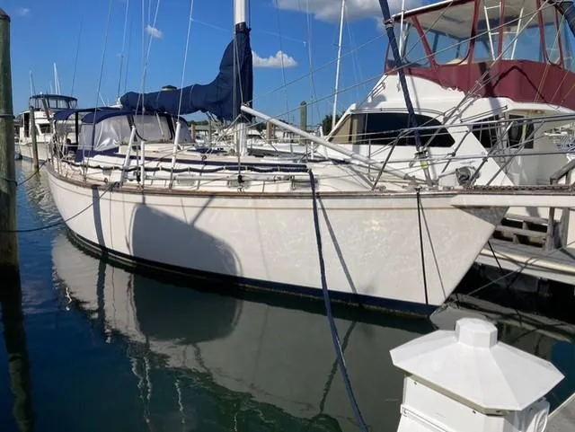 Slide: The Image of 1987 Island Packet 38 sailboat docked at marina, clear sky reflection on water. - 2