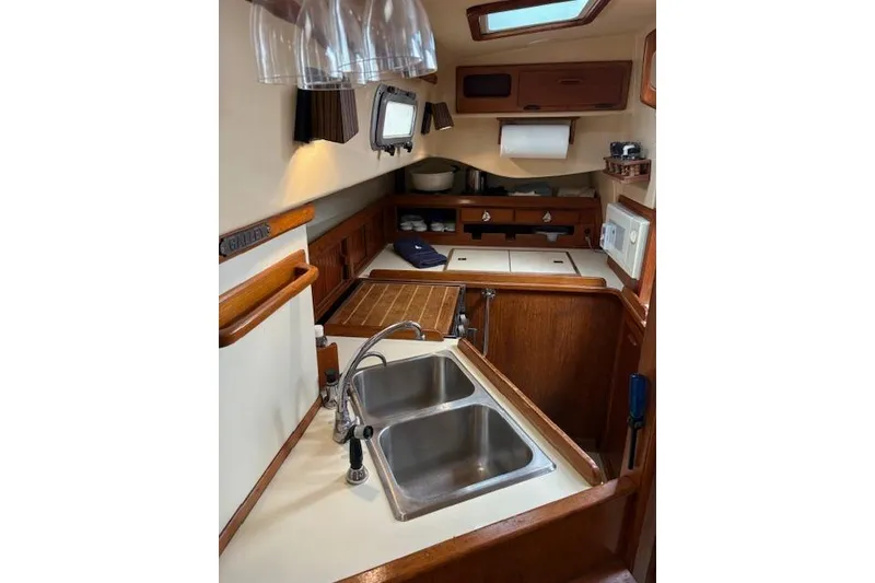 Slide: The Image of 1987 Island Packet 38 yacht interior kitchen with dual sink and wooden cabinetry. - 22