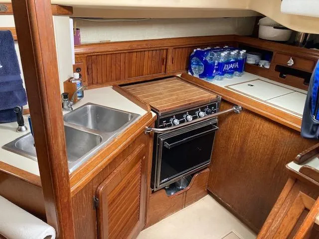 Slide: The Image of 1987 Island Packet 38 yacht kitchen with stove, sink, and storage. - 23