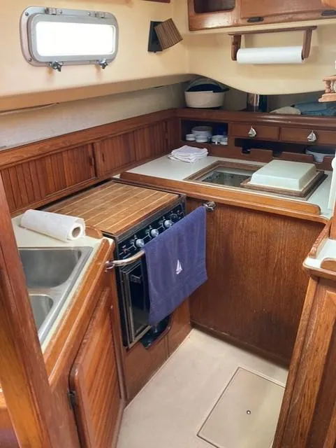 Slide: The Image of 1987 Island Packet 38 yacht kitchen with wooden cabinetry and compact appliances. - 24