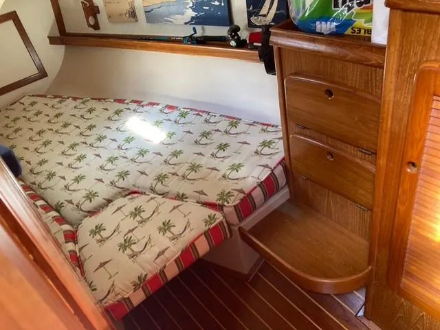 Slide: The Image of 1987 Island Packet 38 cabin with palm tree bedding and wooden storage drawers. - 27