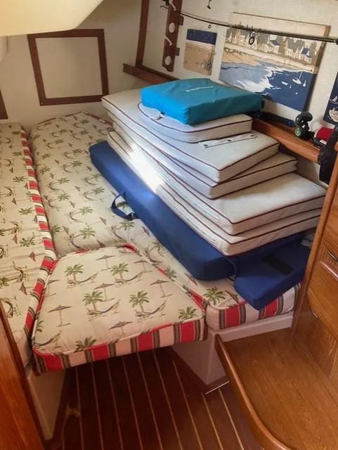 Slide: The Image of Interior of 1987 Island Packet 38 sailboat with stacked cushions and palm tree-patterned bedding. - 28