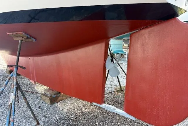 Slide: The Image of 1987 Island Packet 38 sailboat hull with red paint and visible propeller. - 36