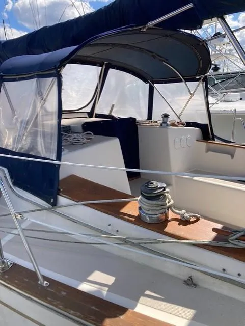 Slide: The Image of 1987 Island Packet 38 sailboat cockpit with blue canopy and winch, under a clear sky. - 9