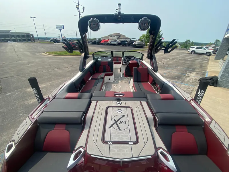 Slide: The Image of 2022 MasterCraft X24 boat interior with red and gray seating, parked in a lot. - 12