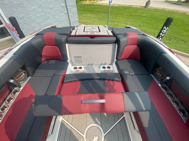 Slide: The Image of 2022 MasterCraft X24 boat interior with red and gray seating, cup holders, and sleek design. - 19