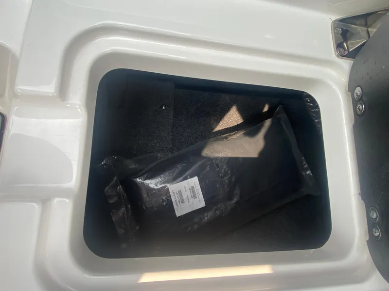 Slide: The Image of Storage compartment in a 2022 MasterCraft X24 boat with a black package inside. - 29