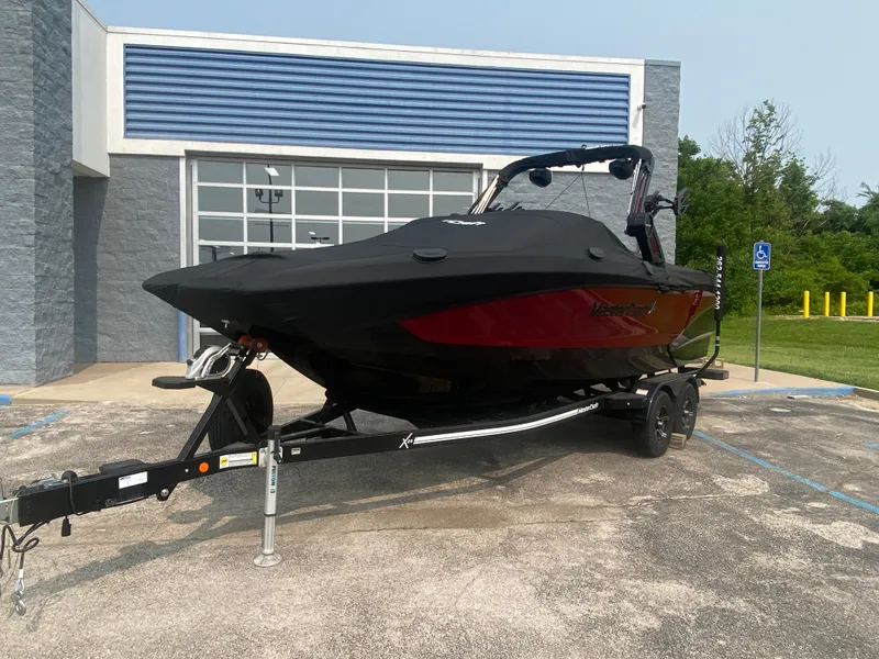 Slide: The Image of 2022 MasterCraft X24 boat on trailer, covered, parked outside a building. - 46