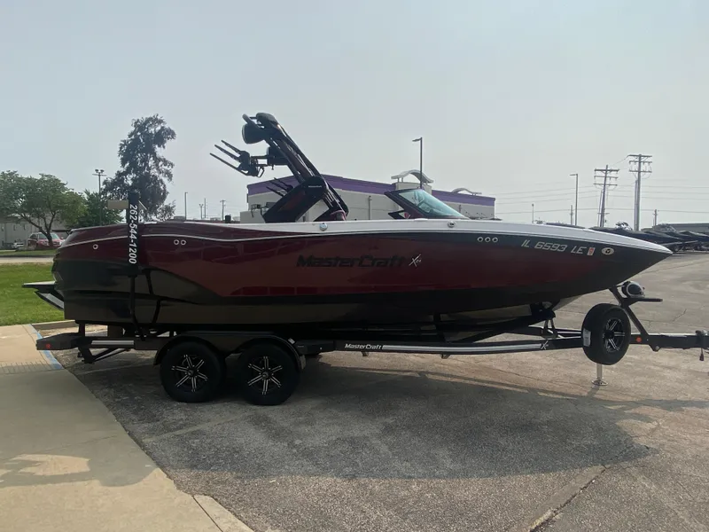 Slide: The Image of 2022 MasterCraft X24 boat on trailer, parked outdoors, side view. - 8