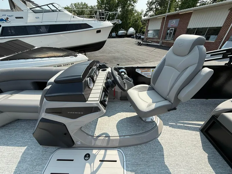 Slide: The Image of 2025 Premier 210 Sunsation RL pontoon boat with spacious seating by a serene marina. - 4