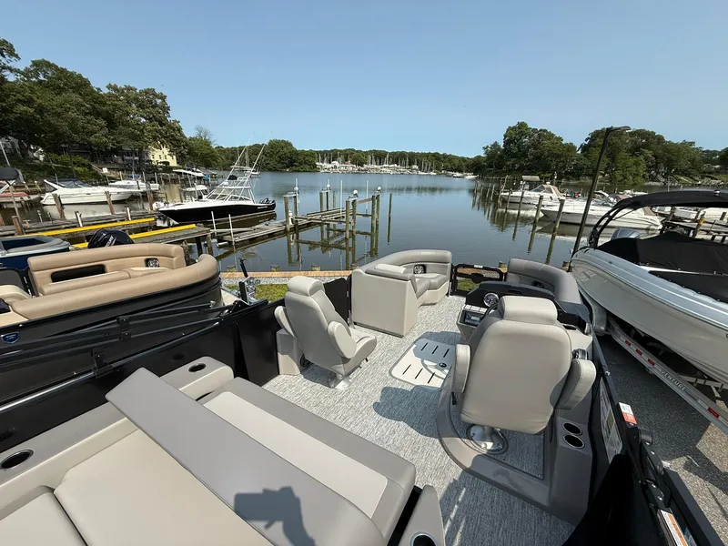Slide: The Image of 2025 Premier 210 Sunsation RL pontoon boat interior with plush seating, docked by a serene marina. - 7