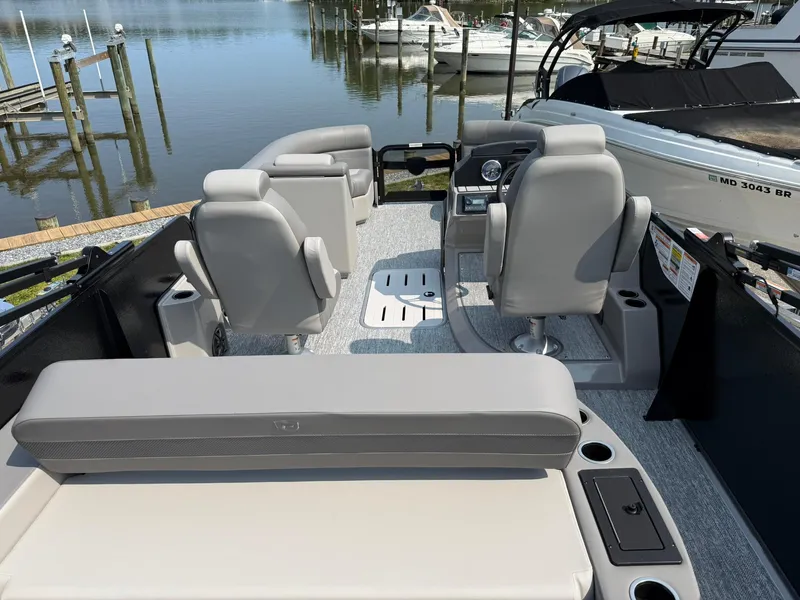 Slide: The Image of 2025 Premier 210 Sunsation RL pontoon boat docked at a scenic marina. - 9