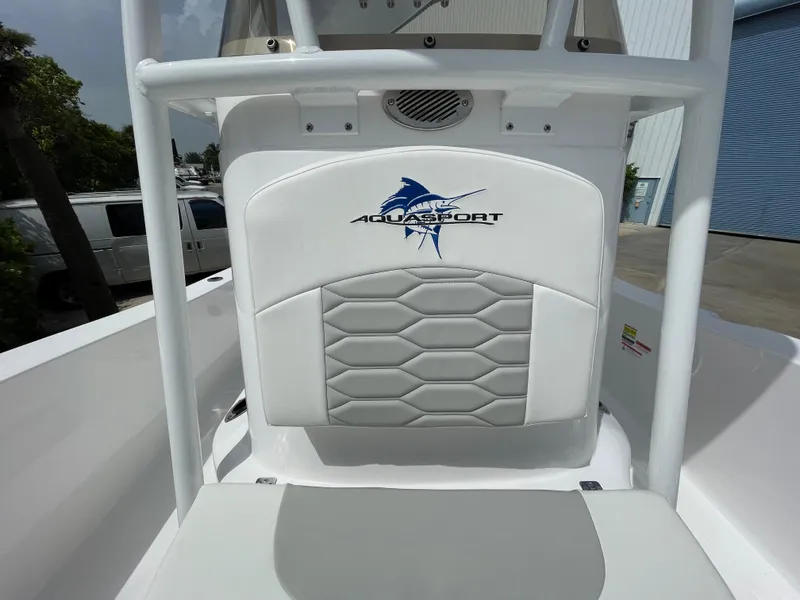 Slide: The Image of 2024 Aquasport 230 Pro Bay boat interior with logo and cushioned seating. - 10