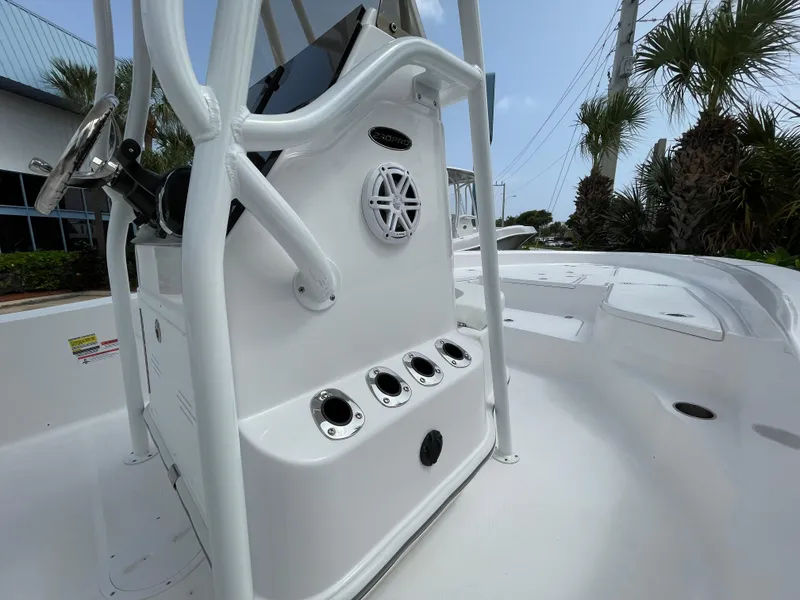 Slide: The Image of 2024 Aquasport 230 Pro Bay boat console with rod holders and speaker, surrounded by palm trees. - 12