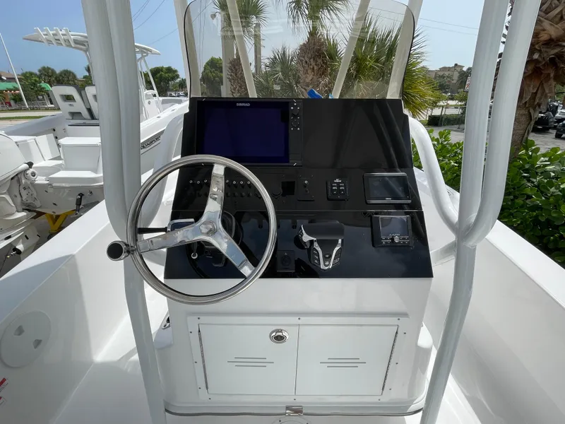 Slide: The Image of 2024 Aquasport 230 Pro Bay boat console with steering wheel and navigation controls. - 13