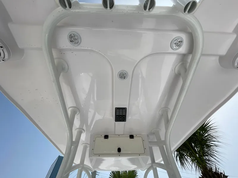 Slide: The Image of 2024 Aquasport 230 Pro Bay boat's T-top underside with integrated lighting and rod holders. - 14