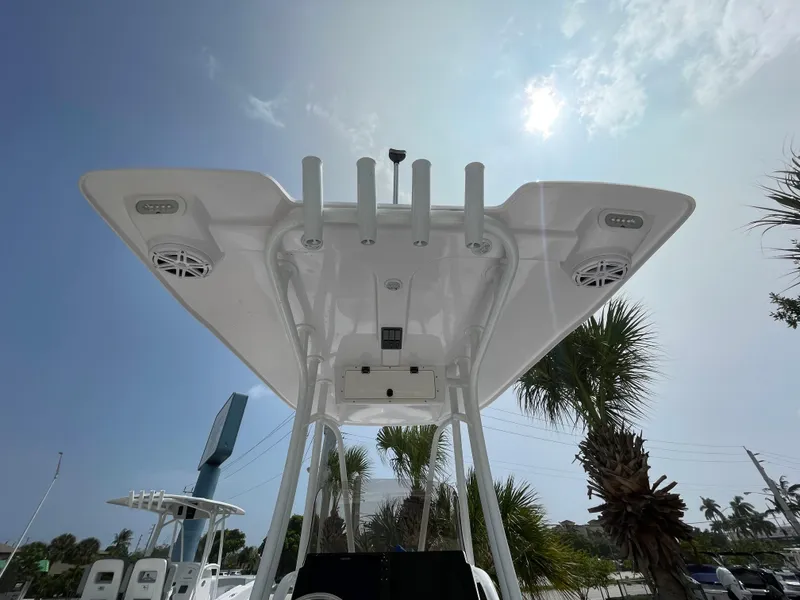 Slide: The Image of 2024 Aquasport 230 Pro Bay boat T-top with rod holders and speakers under a sunny sky. - 15