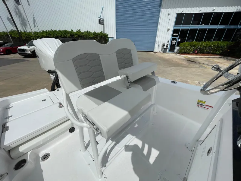 Slide: The Image of 2024 Aquasport 230 Pro Bay boat interior with cushioned seating and steering console. - 17