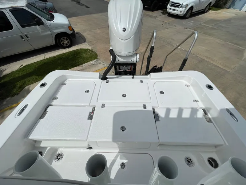 Slide: The Image of 2024 Aquasport 230 Pro Bay boat deck with storage compartments and motor. - 18