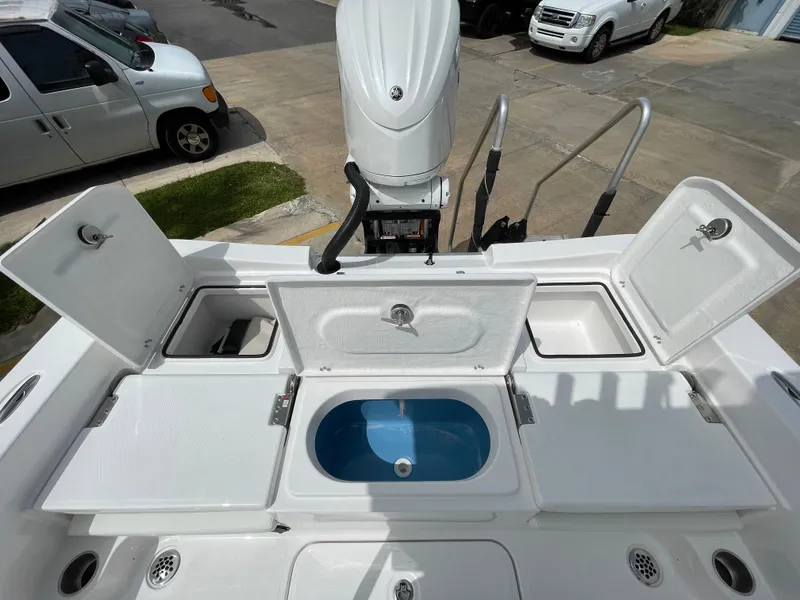 Slide: The Image of 2024 Aquasport 230 Pro Bay boat with open storage compartments and motor, viewed from above. - 21