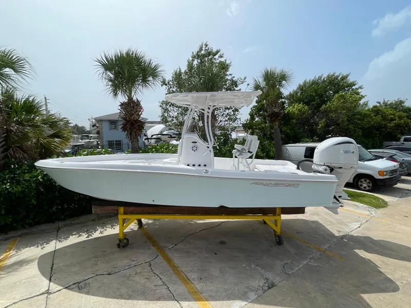 Slide: The Image of 2024 Aquasport 230 Pro Bay boat displayed outdoors on a stand. - 26