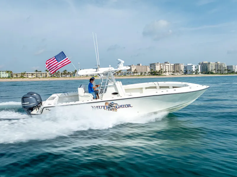 Slide: The Image of 2014 SeaVee 34 boat cruising on water with American flag, cityscape in background. - 14