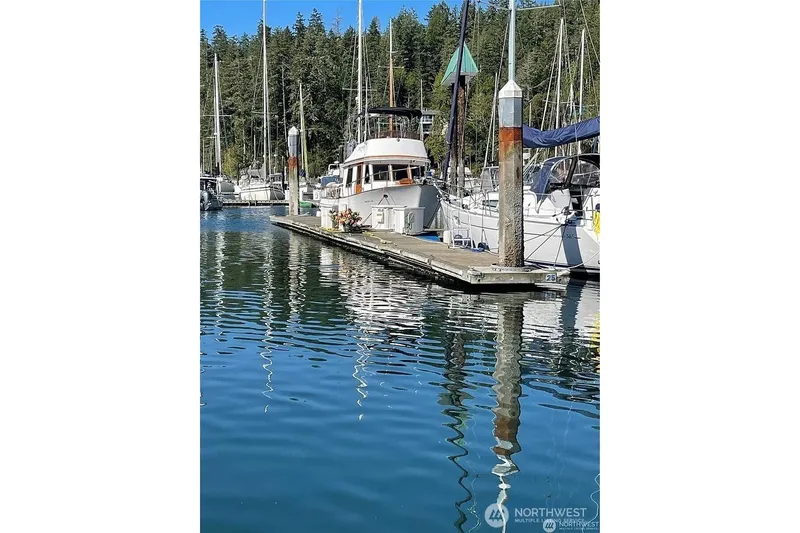 Slide: The Image of 1998 Navigator 53 yacht docked in a serene marina with forest backdrop. - 45